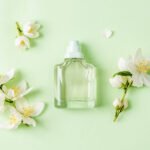 Transparent bottle on green background with blooming flowers
