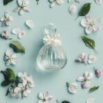Elegant glass perfume bottle surrounded by delicate flowers and leaves
